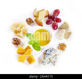 Diverso tipo di formaggio con miele, uva, noci su fondo bianco. Vista dall'alto. Fette di formaggio blu, cheddar, parmigiano, maasdam e brie Foto Stock