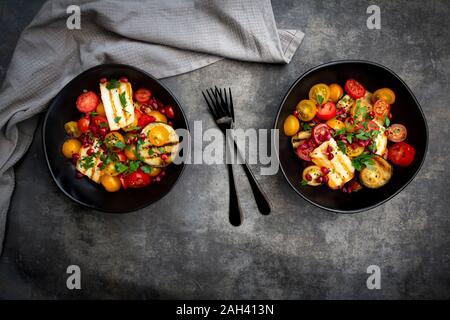 Bocce di Persico con insalata di pomodori e grigliate il formaggio halloumi, melanzana, i semi di melograno, sommacco, sesamo nero e prezzemolo Foto Stock