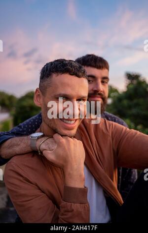 Ritratto di felice coppia gay all aperto al tramonto Foto Stock