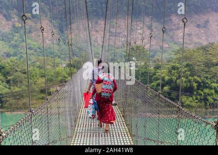 Le donne che attraversano la sospensione ponte sopra il fiume Trishuli in Nepal Foto Stock