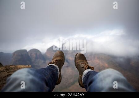 Uomo con un paio di stivali vintage sulla cima di una collina che domina il misty Blyde River Canyon, Sud Africa Foto Stock
