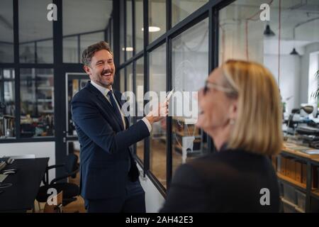 Imprenditore e imprenditrice guardando il disegno sulla lastra di vetro in office Foto Stock