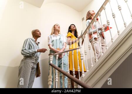 Quattro donne fiducioso a piedi al piano di sopra in scala Foto Stock