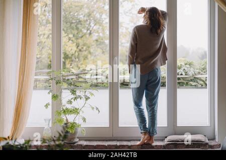 Donna che guarda fuori della finestra, vista posteriore Foto Stock