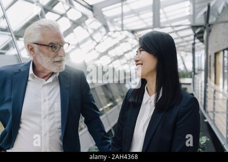 Imprenditore Senior e sorridente imprenditrice nel moderno edificio per uffici Foto Stock