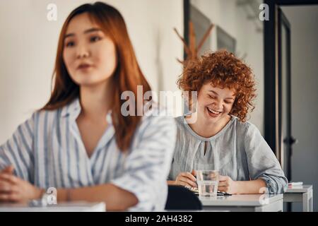 Felice imprenditrice seduto alla scrivania in un workshop Foto Stock