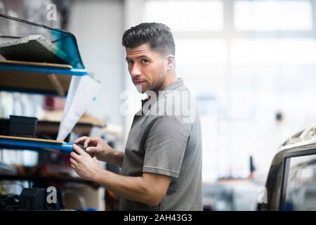 Giovane uomo che lavora in una officina di tappezzeria Foto Stock