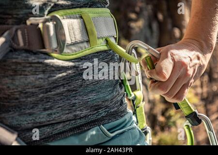 La donna si prepara a salire, mettendo sul cablaggio di arrampicata Foto Stock