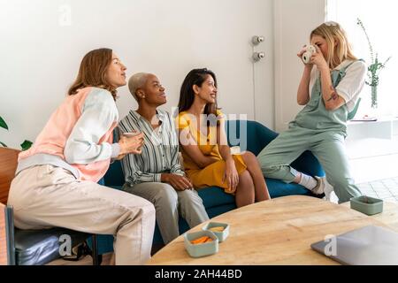 Giovane donna di scattare una foto di amici seduti sul lettino Foto Stock