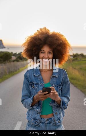Giovane donna su una strada utilizzando lo smartphone, Ibiza Foto Stock