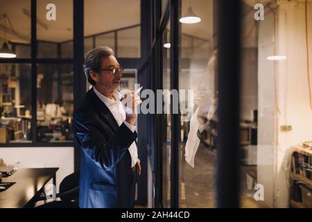 Imprenditore Senior disegno sulla lastra di vetro in office Foto Stock