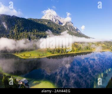 In Germania, in Baviera, Mittenwald, nebbia spessa che fluttua sopra il lago Ferchensee con Wettersteinspitzen mountain in background Foto Stock