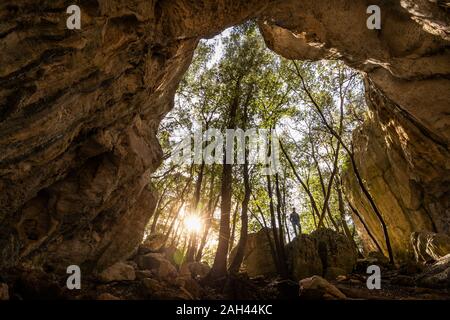 Donna in uscita di una grotta in controluce, Finale Ligure, Liguria, Italia Foto Stock