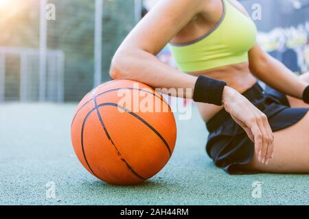 Giovane donna seduta e appoggiata sul basket Foto Stock