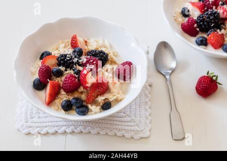 Bocce di fresco muesli vegano con vari frutti di bosco, di uve secche di Corinto e di latte di mandorla Foto Stock