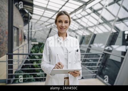 Ritratto di un fiducioso medico donna utilizzando un tablet Foto Stock