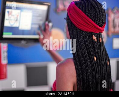 Giovane donna con capelli intrecciati controllare gli ordini su una schermata Foto Stock