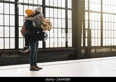 Affettuosa coppia giovane kissing alla piattaforma della stazione, Berlino, Germania Foto Stock