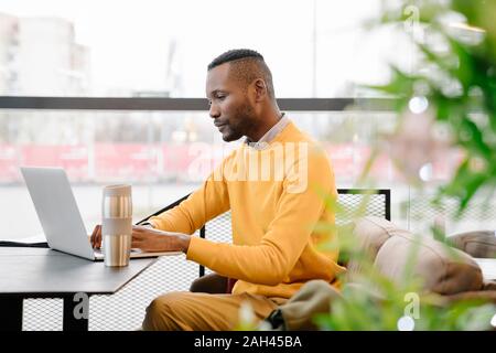 Uomo d affari con computer portatile in un cafe Foto Stock