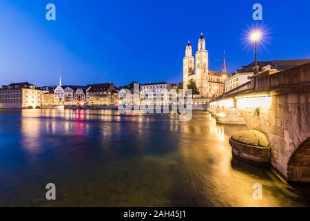 La Svizzera, nel Cantone di Zurigo, Zurigo, fiume Limmat, Munsterbrucke e della città vecchia di edifici lungo illuminato Limmatquai street al crepuscolo Foto Stock