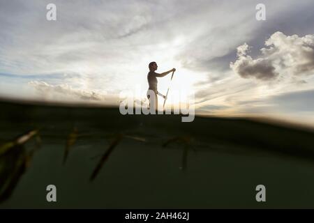 Femmina SUP surfer al tramonto, Bali, Indonesia Foto Stock