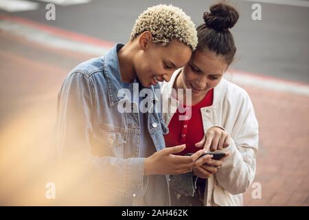 Due giovani donne smartphone il controllo nella città Foto Stock