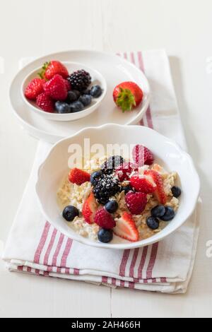 Bocce di fresco muesli vegano con vari frutti di bosco, di uve secche di Corinto e di latte di mandorla Foto Stock