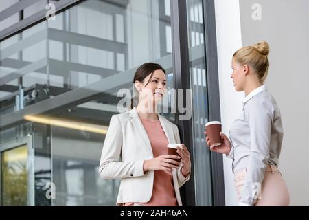 Due imprenditrici avente pausa caffè al di fuori di edificio per uffici Foto Stock