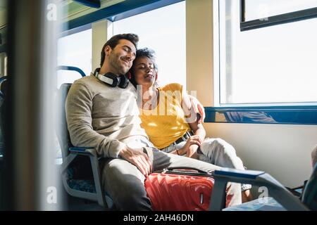 Coppia giovane con gli occhi chiusi rilassante in un treno Foto Stock