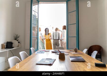 Vista posteriore di quattro donne in piedi sul balcone esterno Sala conferenze Foto Stock