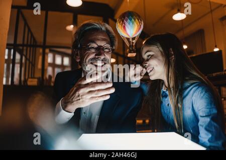 Felice buisinessman senior e la ragazza con mongolfiera e splendente tablet in ufficio Foto Stock