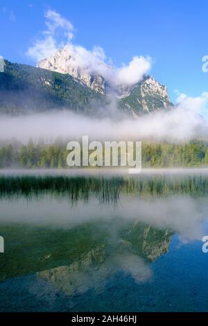 In Germania, in Baviera, Mittenwald, nebbia spessa che fluttua sopra il lago Ferchensee con Wettersteinspitzen mountain in background Foto Stock