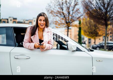 Imprenditrice utilizza lo smartphone proteso al di fuori della finestra della macchina Foto Stock