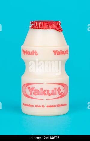 Una bottiglietta di Yakult addolcito probiotici bevanda di latte shot su un sfondo turchese. Foto Stock
