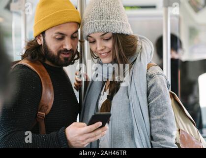 Coppia giovane utilizza lo smartphone su un treno della metropolitana Foto Stock