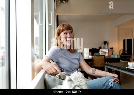 Ritratto di ridere giovane donna seduta in un caffè Foto Stock