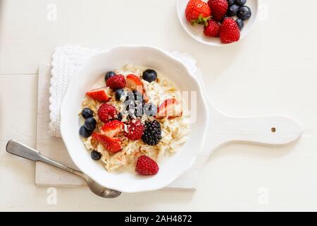 Ciotola di fresco muesli vegano con vari frutti di bosco, di uve secche di Corinto e di latte di mandorla Foto Stock