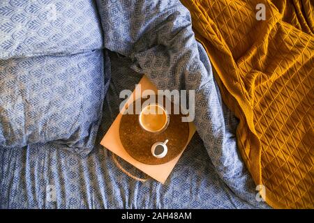 Doppio fondo di vetro con del caffè su un vassoio sul letto con lenzuola moderne in blu classico 2020 anno colore. Foto Stock