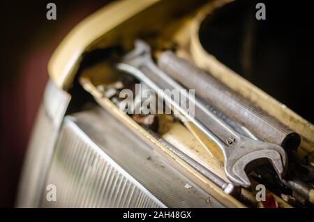 Chiave e viti sulla aprire il cofano di un'auto. Close-up di un utensile manuale vicino al vano motore. Workshop atomica. Messa a fuoco selettiva. Foto Stock