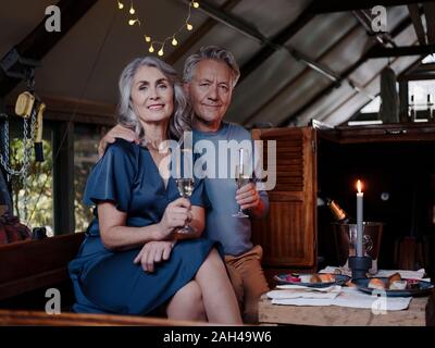 Ritratto di coppia senior avente una cena a lume di candela su una barca in boathouse Foto Stock