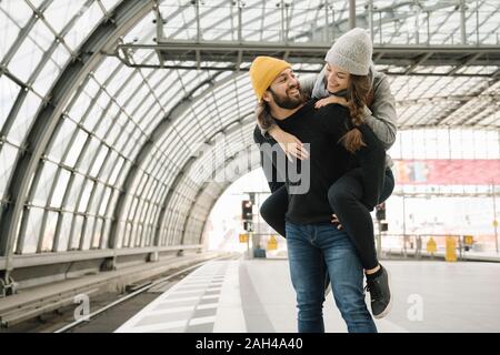 Felice coppia giovane avendo divertimento alla piattaforma della stazione, Berlino, Germania Foto Stock
