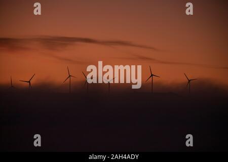 In Spagna, in provincia di Cadice, Tarifa, sagome di turbine eoliche in piedi contro moody sky a Foggy Dawn Foto Stock