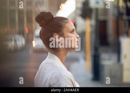 Vista di profilo di fiducioso giovane donna in città Foto Stock