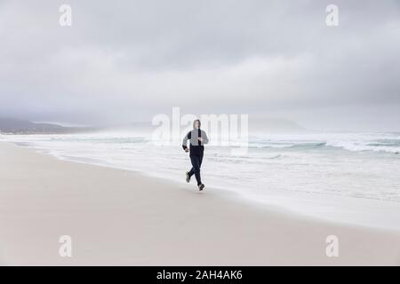 L'uomo jogging sulla spiaggia, Nordhoek, Western Cape, Sud Africa Foto Stock