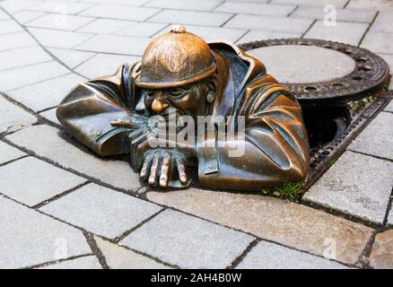 La Slovacchia, Bratislava, scultura in bronzo di uomo in pozzetto Foto Stock