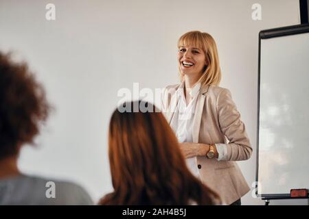 Felice la donna incinta che conduce un workshop in office Foto Stock