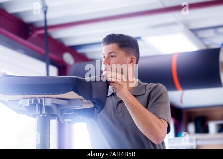 Giovane uomo che lavora in una officina di tappezzeria Foto Stock