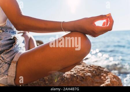 Giovane donna meditando in spiaggia Foto Stock