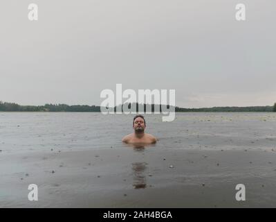 Ritratto di un uomo con gli occhi chiusi bagno nel lago sul giorno di pioggia Foto Stock