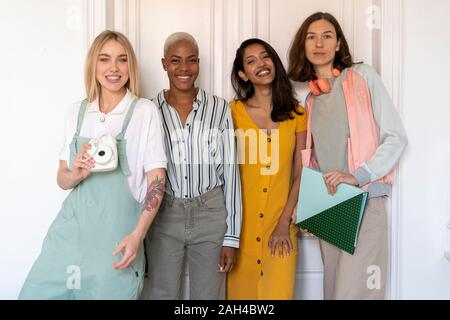 Ritratto di quattro donne sorridente in piedi a fianco a fianco Foto Stock